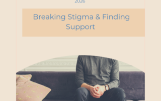 Man seated indoors in a calm, neutral setting, representing reflection and emotional support related to men’s mental health in 2026